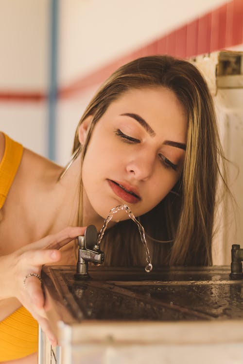 Beautiful women Drinking Water from a water Fountain
